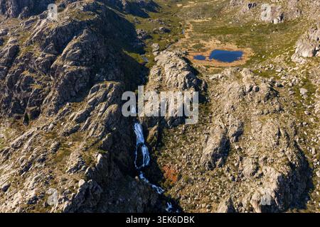 Vue aérienne de Vale da Candeeira avec sa cascade et son petit lac bleu niché parmi les falaises de granit accidentées de Serra da Estrela à Manteigas, Dist Banque D'Images