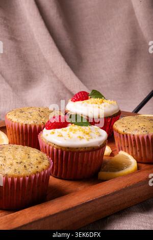 Un gros plan, à hauteur des yeux, de plusieurs muffins aux graines de pavot citron fraîchement cuits disposés sur un plateau en bois. Banque D'Images