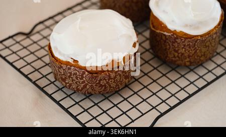 Gâteaux de Pâques traditionnels sans gluten (pains de Pâques Kulich) recouverts de glaçage blanc refroidissant sur une grille métallique. Gros plan Banque D'Images