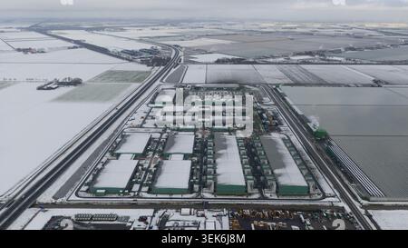 Vue aérienne d'un grand centre de données industriel et de serres entourées de champs agricoles enneigés à Middenmeer, Hollande du Nord, ne Banque D'Images
