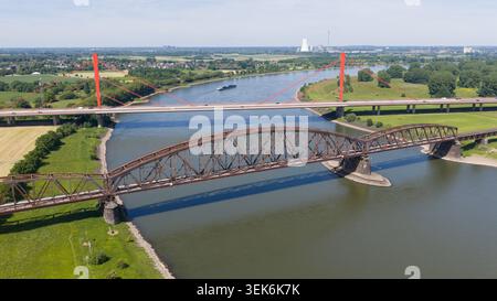 Vue aérienne du pont ferroviaire historique Haus-Knipp et du pont moderne Beeckerwerth traversant le Rhin avec des cheminées industrielles à Duisburg Banque D'Images