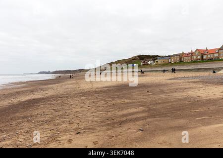 Sandsend, Yorkshire, Royaume-Uni, Angleterre, Une large vue côtière à Sandsend près de Whitby, montrant la plage de sable avec des galets dispersés et des gens marchant le long Banque D'Images