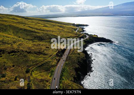 Une vue aérienne époustouflante d'une route côtière sinueuse sur Maui, Hawaï, mettant en valeur des collines verdoyantes, des falaises spectaculaires et l'immense océan Pacifique Banque D'Images