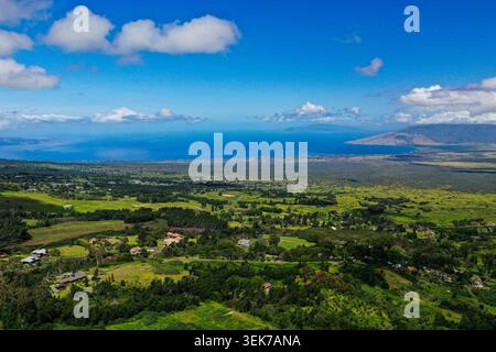 Une vue aérienne à couper le souffle capture les champs verdoyants, les maisons dispersées et le littoral étendu de Maui, Hawaï, avec les eaux bleues du P. Banque D'Images