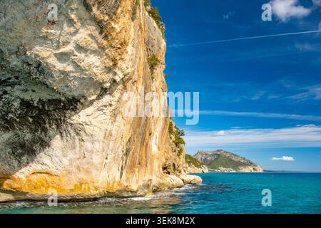 Les eaux bleues vives invitent à l'aventure tandis que les kayakistes naviguent sur la côte pittoresque de la Sardaigne. Les falaises spectaculaires et le ciel serein renforcent cette belle Banque D'Images
