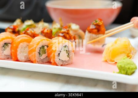 Assiette d'assortiment de sushis artistiques dans un restaurant japonais. Rouleaux frais vibrants disposés comme un affichage culinaire appétissant. Menu coloré présentant une variété de saveurs traditionnelles et d'art culinaire Banque D'Images