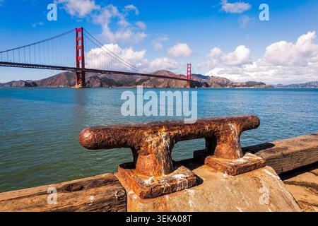 Borne rouillée sur une jetée en bois avec l'emblématique Golden Gate Bridge traversant la baie Banque D'Images
