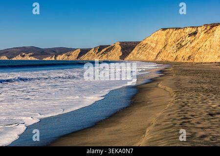 Les vagues roulantes s'écrasent sur le rivage sablonneux sous les impressionnantes falaises de Drakes Beach Banque D'Images