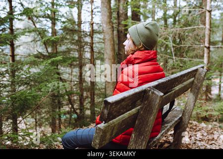 la jeune femme fait des randonnées dans la forêt, s'assoit sur un banc, se repose et réfléchit seule Banque D'Images