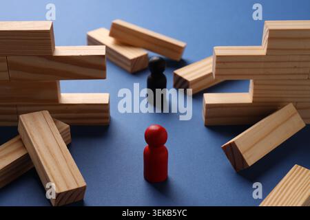 Mur en bois effondré fait de blocs et de figures humaines sur fond bleu, gros plan. Surmonter les obstacles Banque D'Images