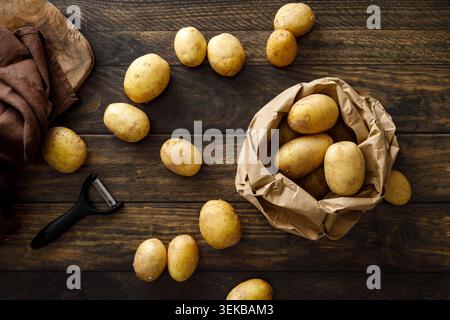 Pommes de terre entières crues fraîches sur une table en bois rustique, vue de dessus Banque D'Images