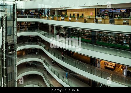 Intérieur du centre commercial Toptani à Tirana, Albanie, montrant des balcons courbes à plusieurs niveaux, des balustrades en verre, un ascenseur et un Burger King. Banque D'Images