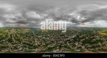Vue panoramique à 360° de Panorama aérien sphérique complet capture une ville au Kirghizistan. Les zones résidentielles denses et les champs agricoles s'étendent vers des montagnes lointaines sous A.