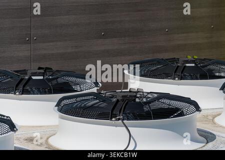 Vue rapprochée de plusieurs climatiseurs industriels installés à l'extérieur près d'un mur sombre sur un bâtiment commercial. Banque D'Images