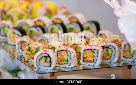 Rangées soigneusement disposées de rouleaux de sushi avec garnitures et garnitures colorées Banque D'Images