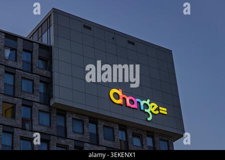 Amsterdam, pays-Bas : vue nocturne de la façade du bâtiment résidentiel Modern change avec son logo lumineux multicolore. Banque D'Images