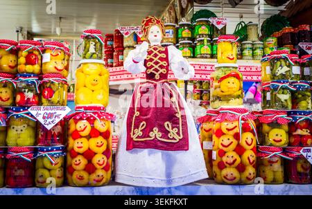 Budapest, Hongrie - 24 juillet 2013. Poupée hongroise traditionnelle se dresse parmi les pots créatifs de cornichons au marché. Banque D'Images