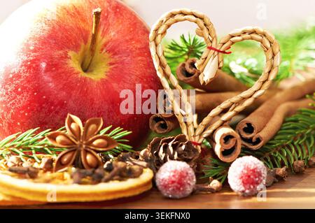 Décorations de Noël comportant des pommes, des coeurs, des bâtonnets de cannelle, de l'anis étoilé, des clous de girofle, branches d'épinette, ornements et pommes de pin Banque D'Images