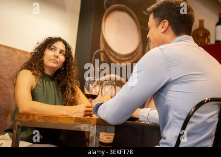 Jeune couple passant du temps de qualité ensemble tout en dégustant du vin rouge dans un restaurant. Banque D'Images