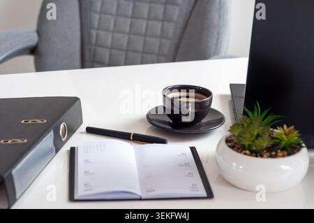 Le planificateur ouvert repose à côté du café et du stylo Banque D'Images