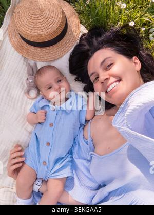 Heureuse mère et bébé se relaxant à l'extérieur sur une couverture Banque D'Images