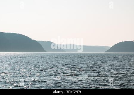 Spectaculaire Hazy Skyline au-dessus de Calm Waters et Rolling Hills en arrière-plan Banque D'Images
