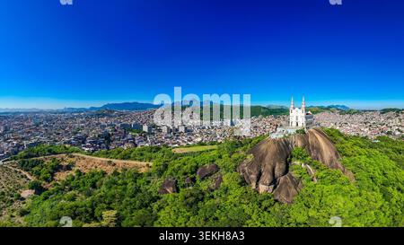Vue aérienne panoramique de la basilique Sanctuaire de notre-Dame de Penha construit sur un rocher avec vue sur le quartier derrière dans la ville de Rio de Janeiro Banque D'Images