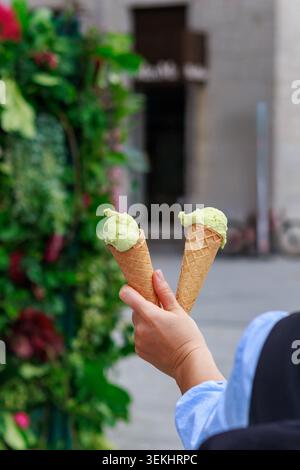 Femme tenant deux cônes de crème glacée à la pistache dans un cadre urbain extérieur Banque D'Images