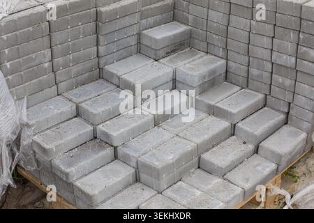 Pile soigneusement empilée de pavés de béton gris sur une palette en bois préparée pour les travaux de construction. Banque D'Images