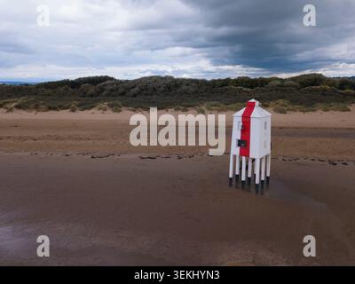 Vue par drone du phare de Burnham‑on‑Sea Low sur la plage de sable, capturant sa structure rouge et blanche frappante contre les dunes côtières et le ciel Banque D'Images