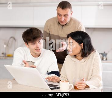Une famille amicale regarde quelque chose ensemble sur Internet ou des chats vidéo via un ordinateur portable Banque D'Images