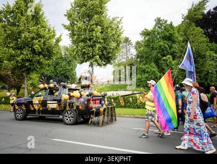 Klagenfurt, Autriche - 30 mai 2026 : Pride Parade avec un camion décoré et des participants portant un drapeau arc-en-ciel dans une rue animée entourée de b Banque D'Images