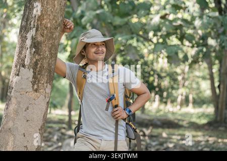 Jeune homme Backpacker voyageant seul dans la forêt. Voyageur masculin attrayant marchant dans le bois de la nature pendant le voyage de vacances Banque D'Images