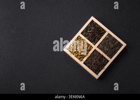 Une boîte en bois avec plusieurs types de thé séché, vert, noir, fruit, et camomille. Thé sec dans la boîte comme toile de fond pour votre conception Banque D'Images
