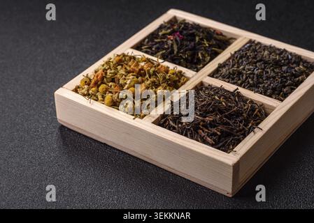 Une boîte en bois avec plusieurs types de thé séché, vert, noir, fruit, et camomille. Thé sec dans la boîte comme toile de fond pour votre conception Banque D'Images