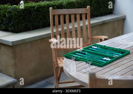 Plateau de backgammon vert installé sur une table de jardin en bois pour un jeu en plein air dans un cadre de patio privé. Banque D'Images