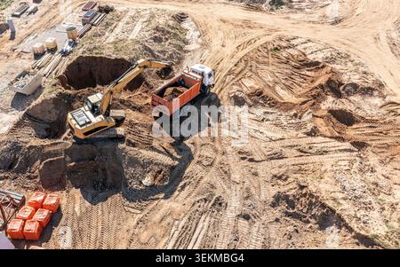 la pelle chargera du sable dans un tombereau à benne basculante. terrassement sur chantier. vue aérienne. Banque D'Images
