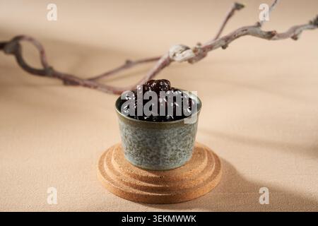 La tasse de poterie à glaçage vert est remplie de perles de sucre brun, qui sont douces et brillantes, et les branches sont décorées avec un fond chaud. Banque D'Images