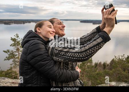 Jeune femme souriante posant avec la mère prenant selfie par téléphone intelligent à l'extérieur Banque D'Images