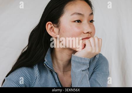Jeune femme contemplative regardant loin en s'appuyant sur le coude Banque D'Images