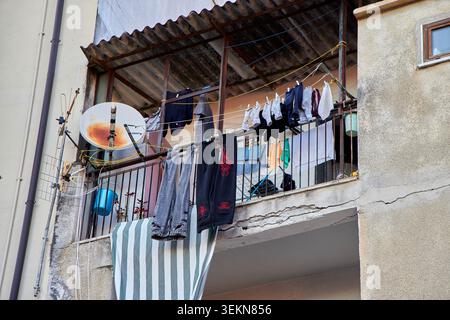 Buanderie suspendue à une corde à linge sur un vieux balcon rustique en Italie. Banque D'Images