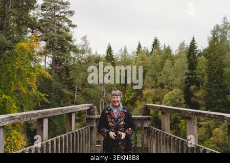 Heureuse femme mature debout sur le pont dans la forêt Banque D'Images