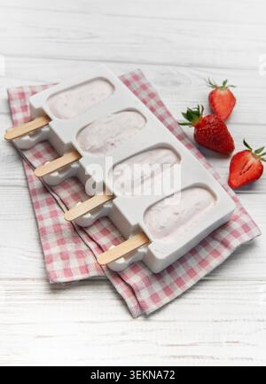 Fraise yogourt popsicles dans un moule sur une serviette à carreaux avec des fraises fraîches Banque D'Images