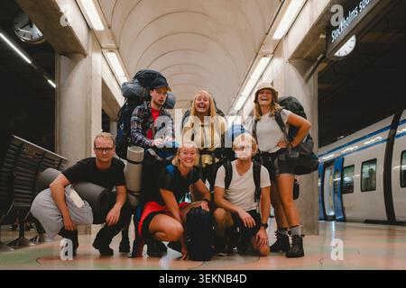 Portrait d'un groupe d'amis heureux hommes et femmes posant avec des bagages à la plate-forme du métro Banque D'Images
