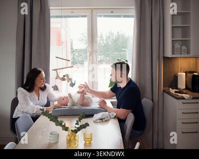 Parents passant du temps libre avec bébé garçon allongé sur un petit lit à la maison Banque D'Images