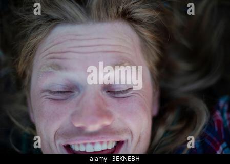 Directement au-dessus du plan de l'homme heureux avec les yeux fermés couchés dehors Banque D'Images