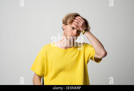 Jeune homme souffrant de maux de tête sévères ou de migraine, ressentant une douleur intense et un inconfort dans son front, éprouvant stress, maladie, épuisement Banque D'Images