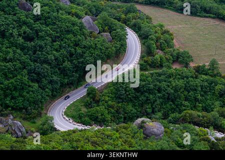 Voitures sur une route sinueuse à travers la forêt verte dans Météores Grèce Banque D'Images