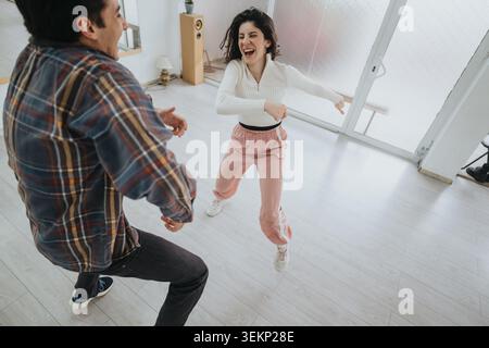 Jeune dansant joyeusement ensemble à la maison dans un espace de vie moderne lumineux Banque D'Images