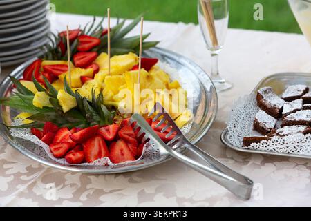 Plateau de fruits avec fraises fraîchement coupées et ananas offrant des options de desserts sains Banque D'Images